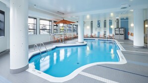An indoor swimming pool with clear water, surrounded by white walls and columns, with seating areas and windows. - Holiday Inn Hotel & Suites Ottawa Kanata by IHG (Ottawa)