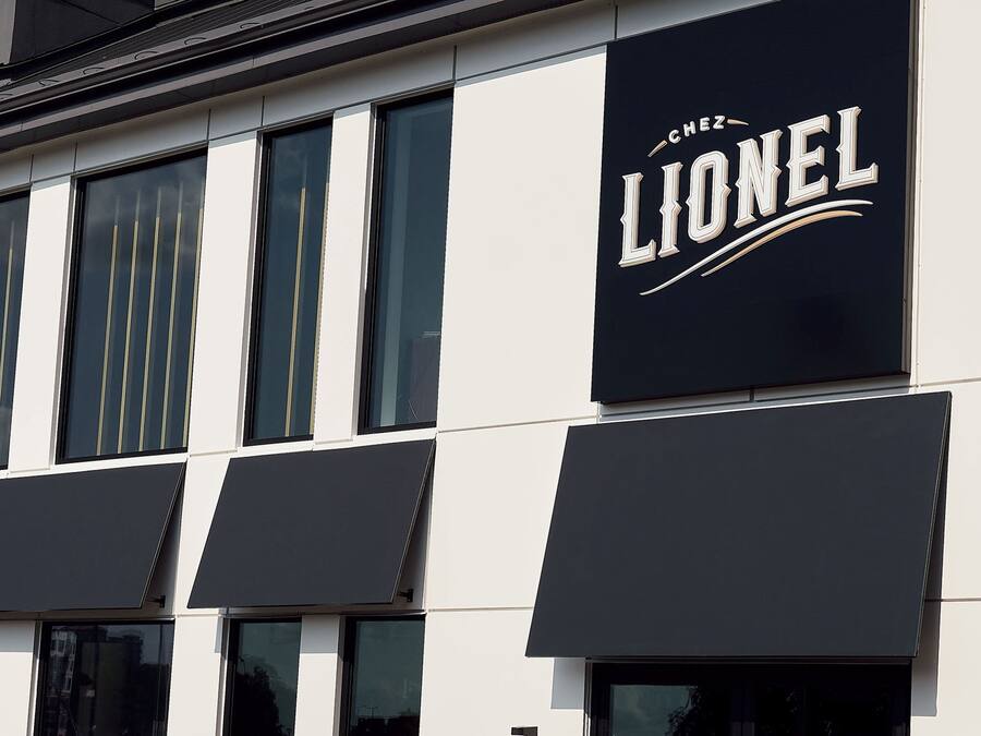 Un edificio con fachada blanco y negro, que presenta un llamativo letrero 'LIONEL' en el lado derecho.