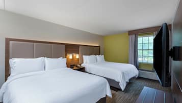 A hotel room with two beds, a flat-screen TV, and a window with curtains.