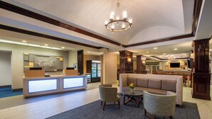 A hotel lobby with a reception desk, seating area, and a large chandelier. - Holiday Inn Express State College at Williamsburg Square by IHG (State College)