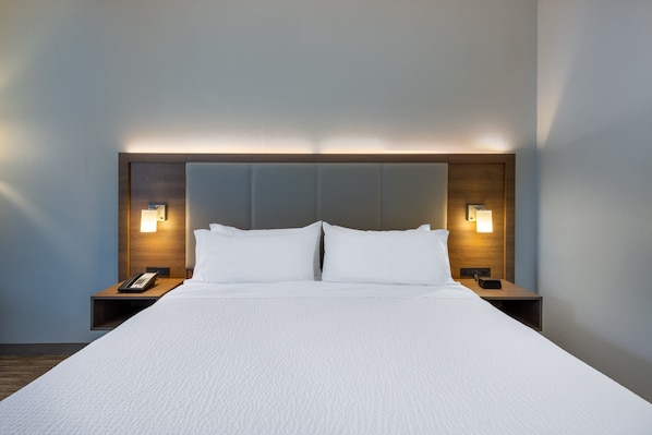 Ein Hotelzimmer mit einem großen Bett, zwei Nachttischen und Wandleuchten.