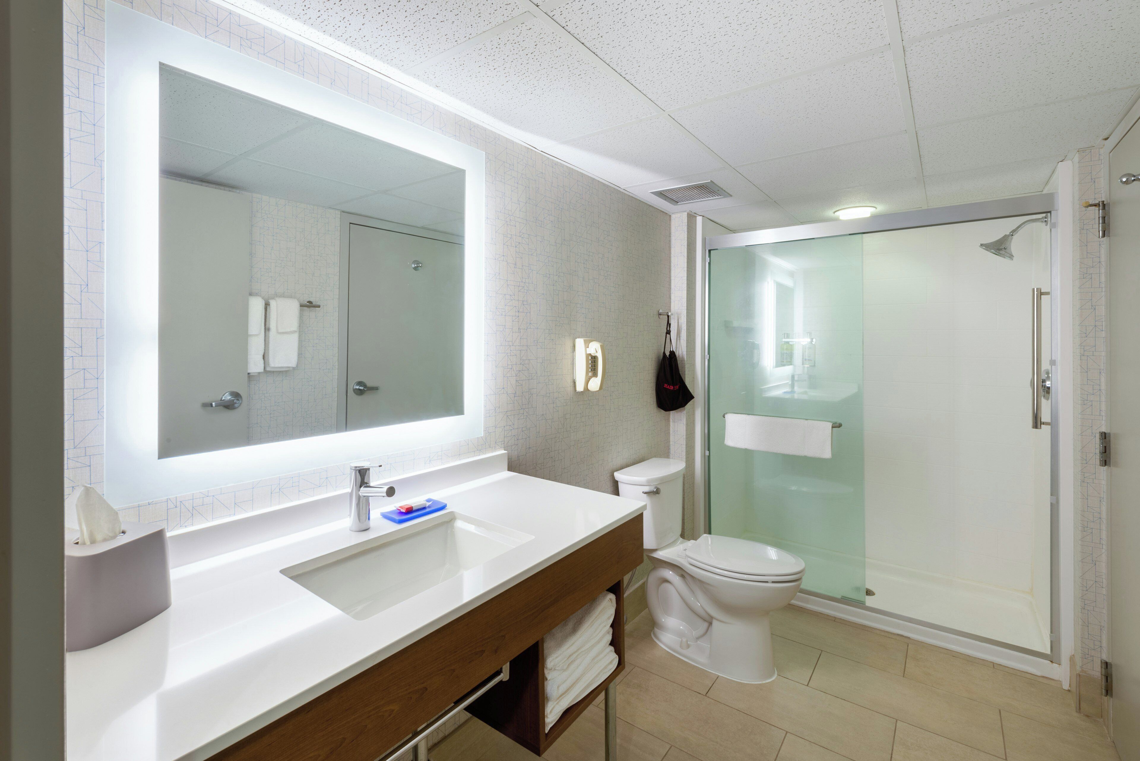 Un bagno moderno con uno specchio grande, un lavandino bianco, un water e una cabina doccia in vetro.