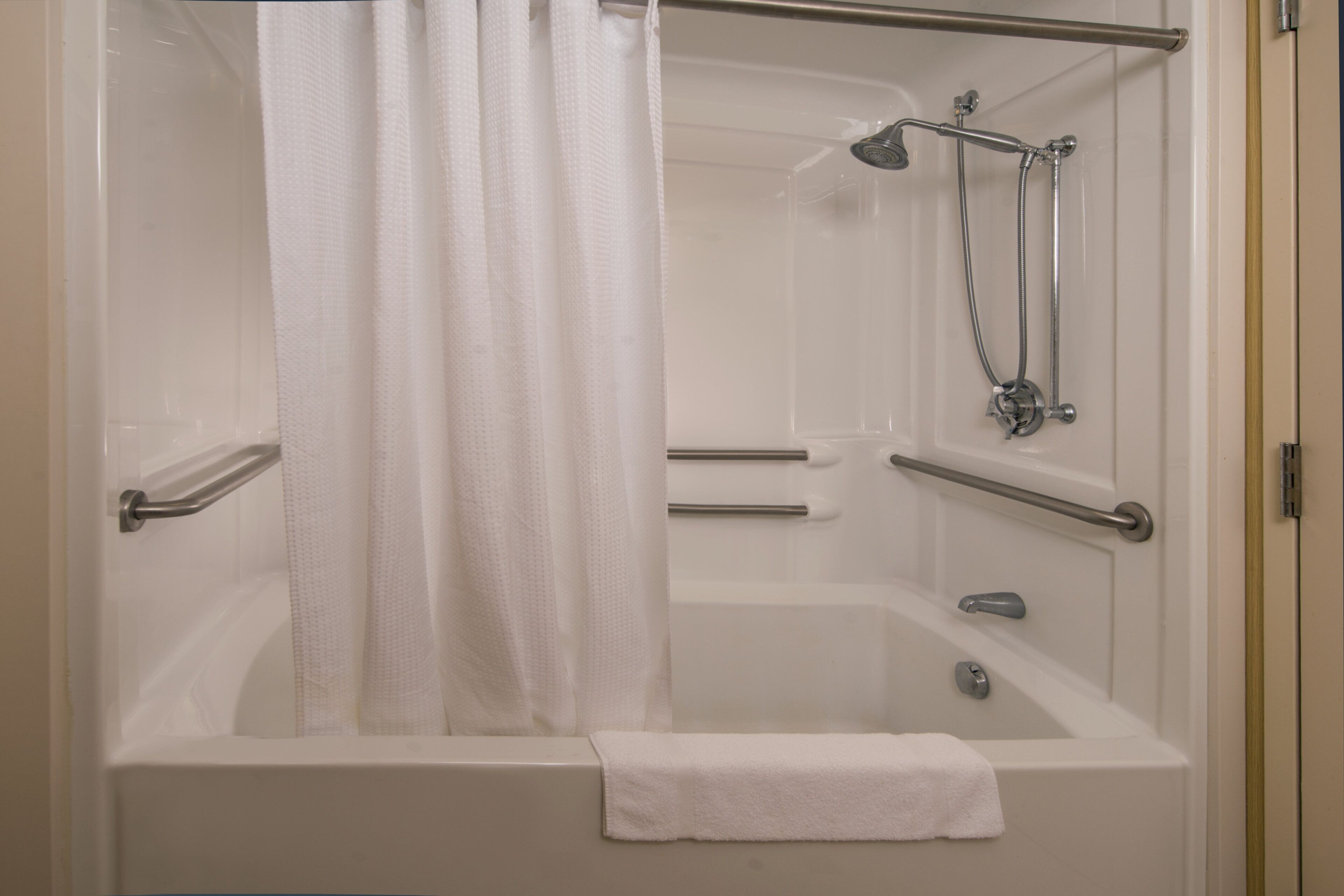 A walk-in shower with a glass door, a handheld showerhead, and a towel rack.