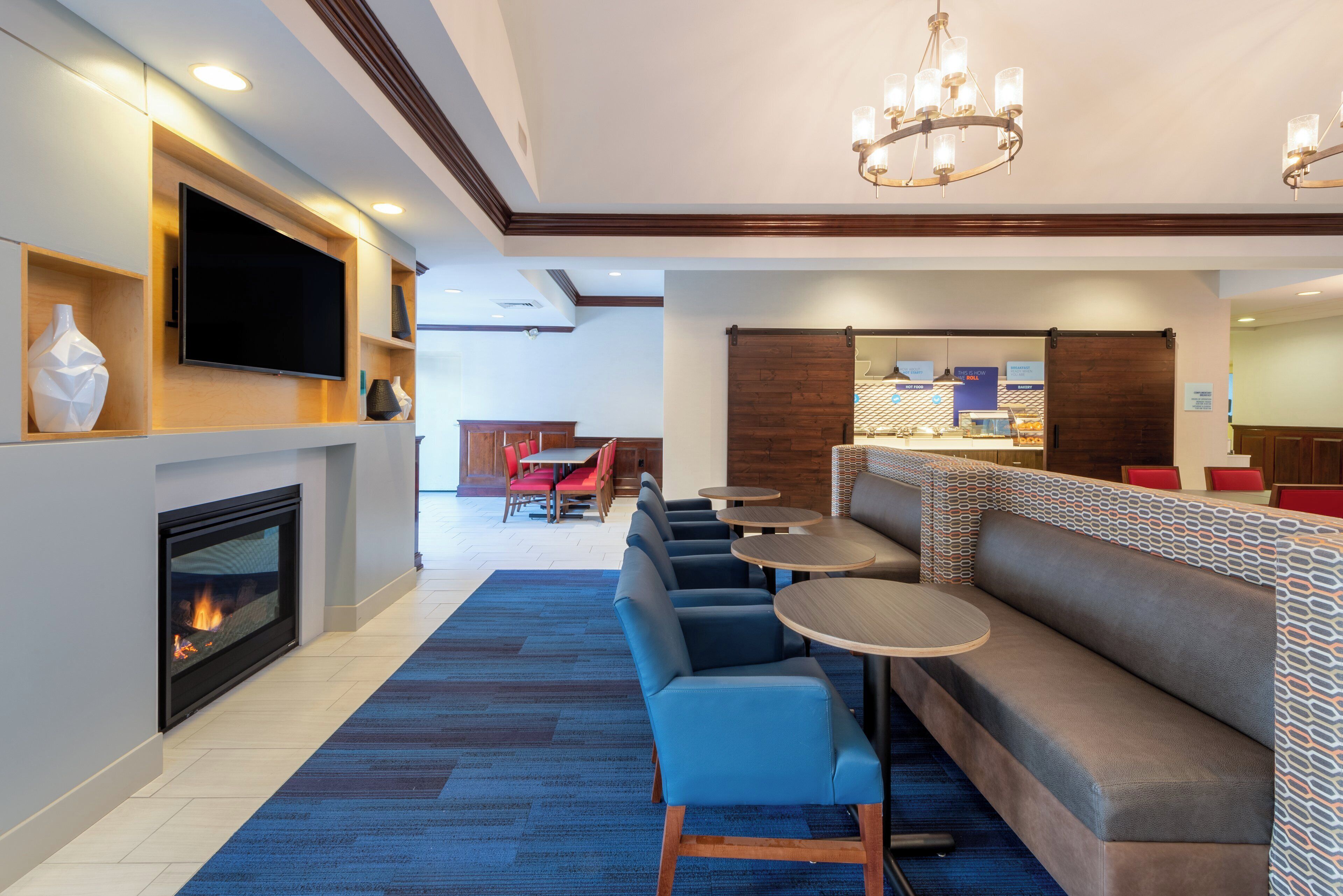 Um hall de hotel com lareira, televisão, área de estar e bar.