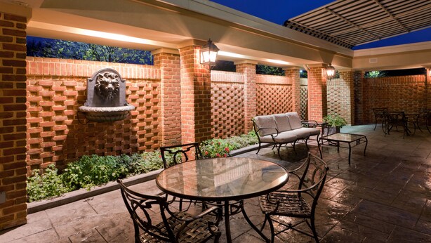 An outdoor patio with brick walls, a stone fountain, and metal furniture.