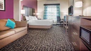 Una habitación de hotel con cama, sofá, escritorio y televisión.