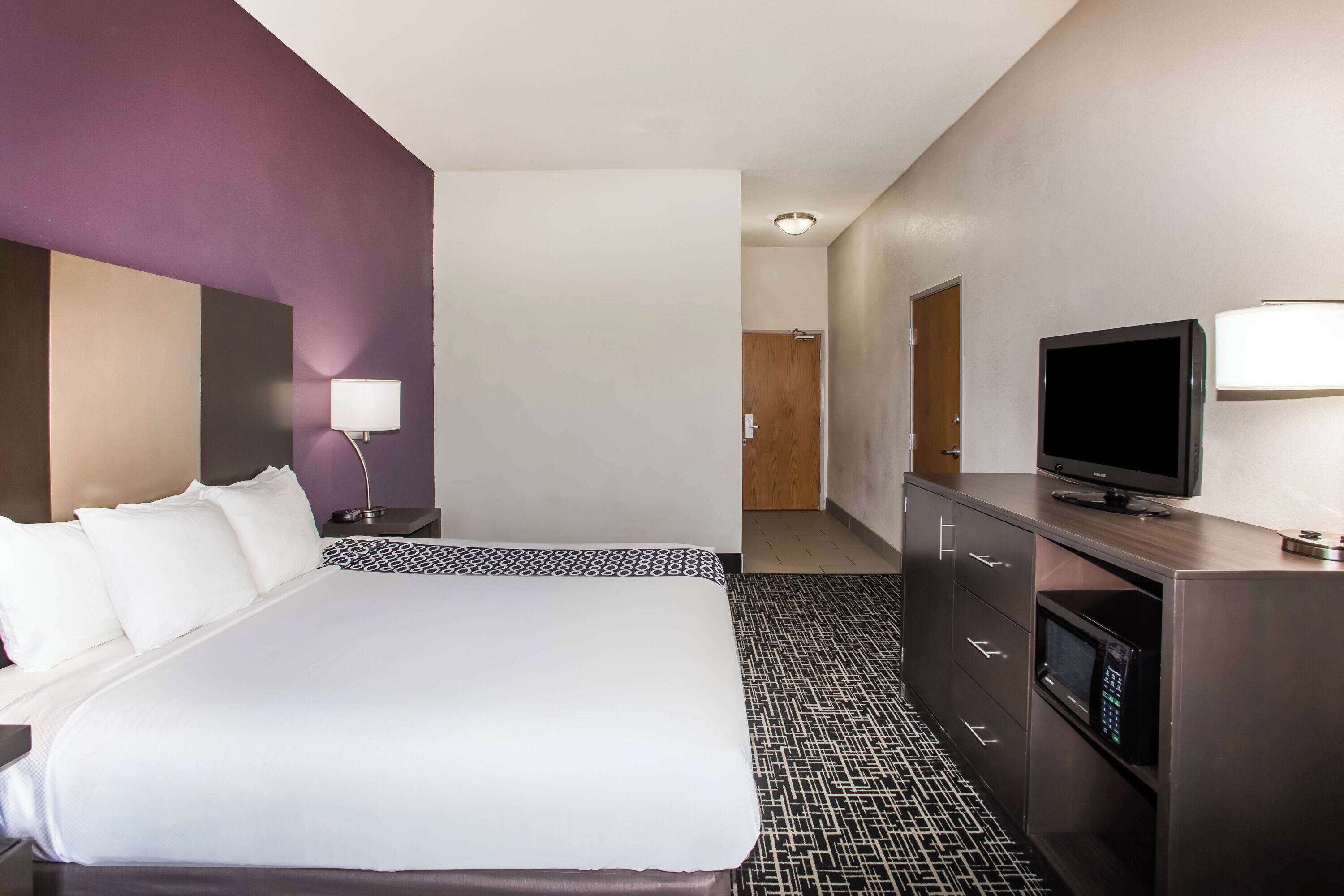 A hotel room with a large bed, a TV, a desk, and a microwave.