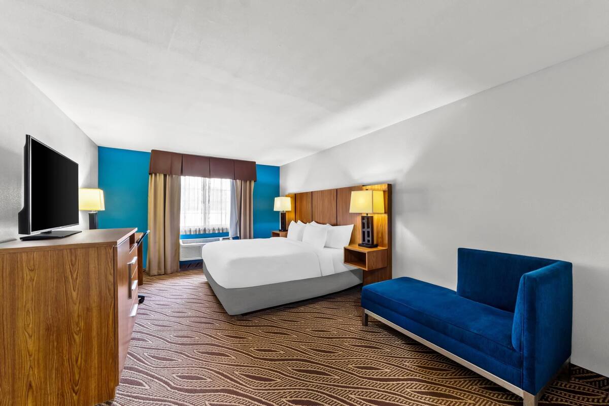 Une chambre d’hôtel avec un lit, un canapé bleu, une télévision et un bureau.
