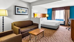 A hotel room with a bed, a sofa, a small table, a desk, a chair, and a lamp. - Quality Inn & Suites San Antonio Airport - Stone Oak (San Antonio)