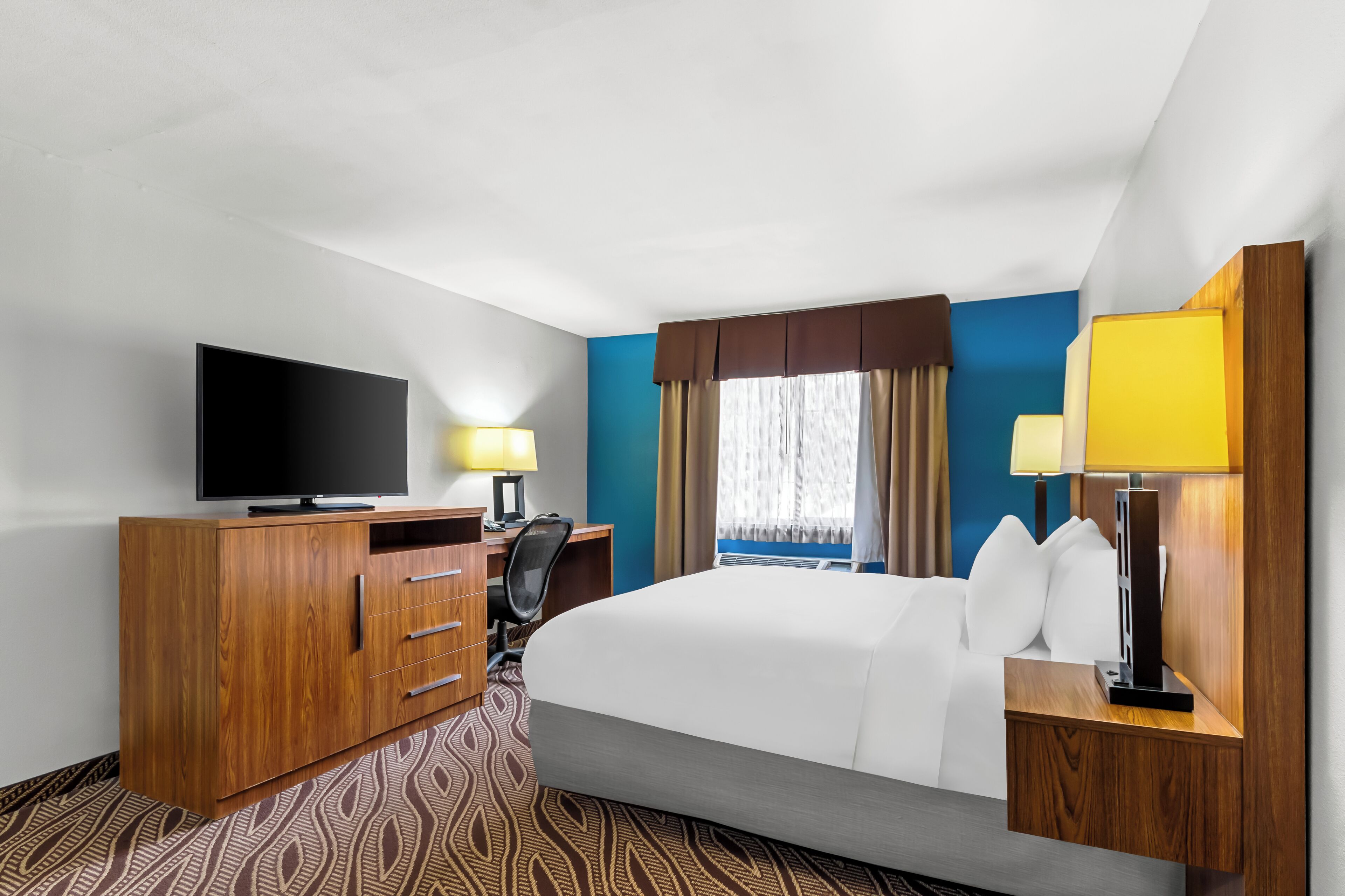 A hotel room with a bed, a TV, a desk, and a wardrobe.