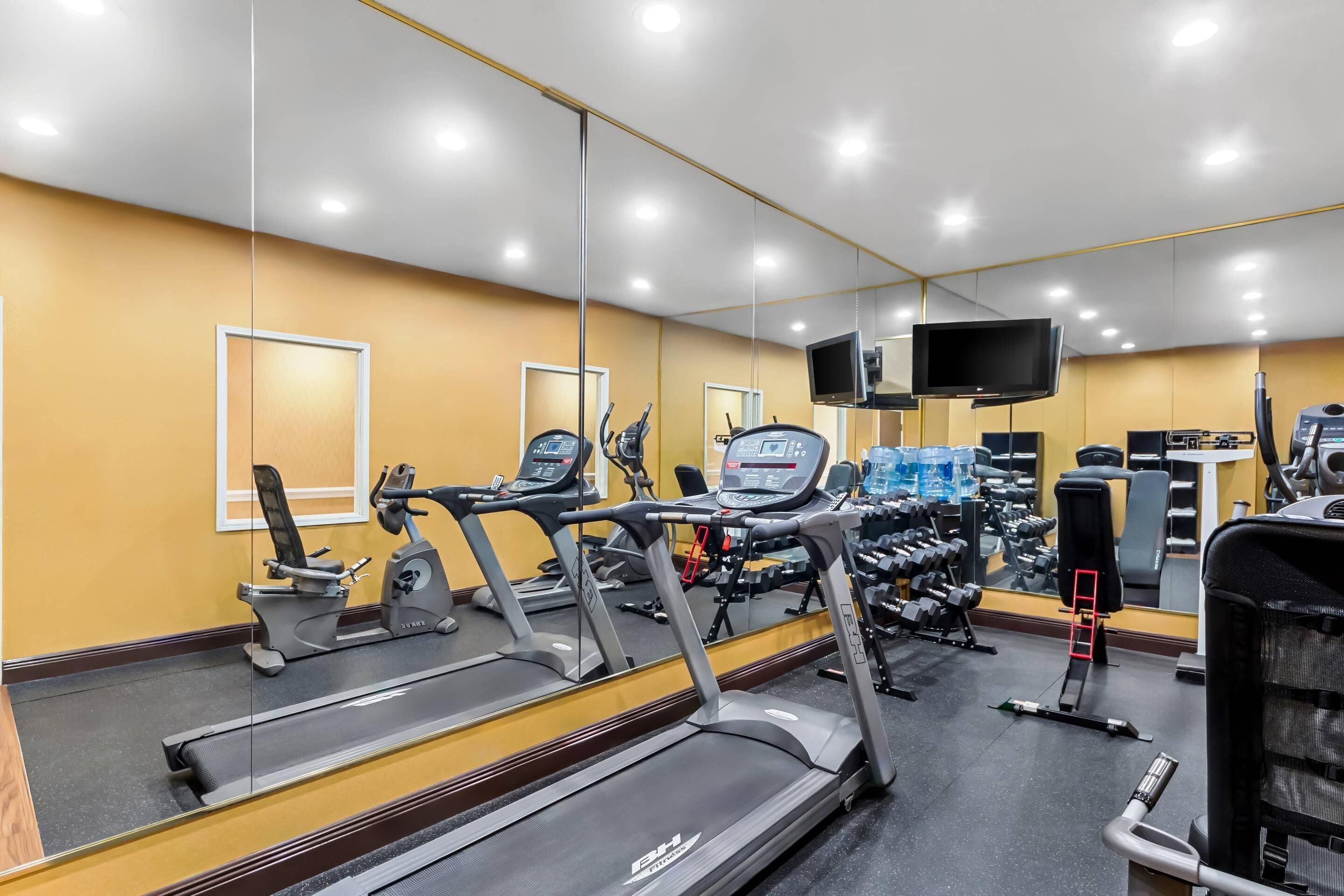 Une salle de sport équipée de tapis de course, de vélos d’exercice et d’appareils de musculation.