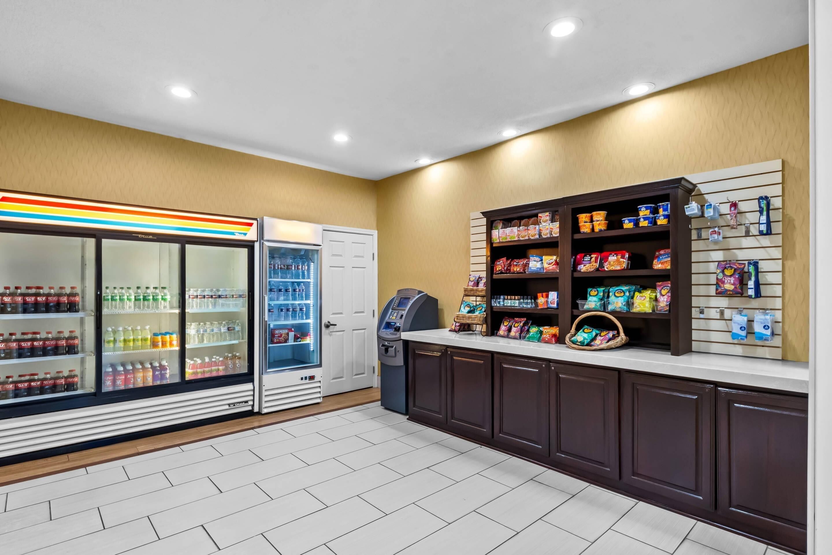 Quarto limpo e bem iluminado com geladeira abastecida de bebidas, um expositor de lanches e um quiosque de autoatendimento.