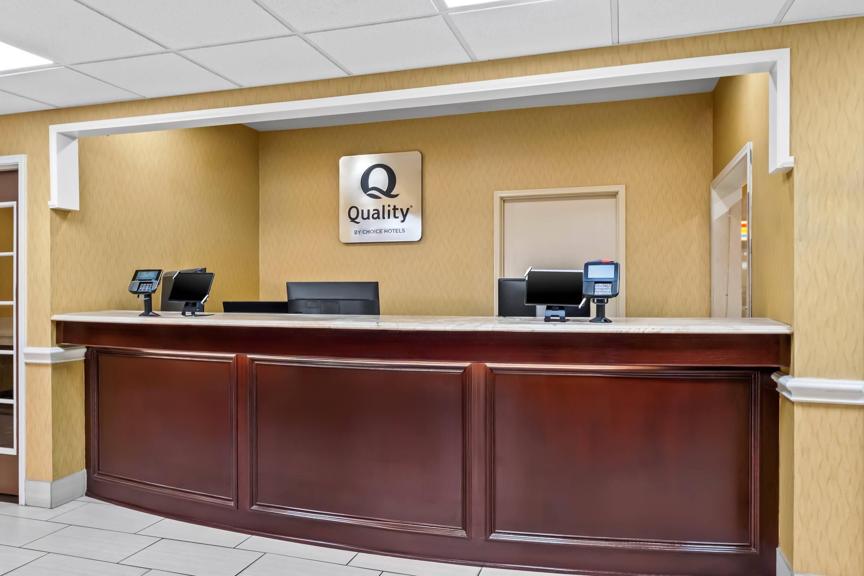 Un comptoir d’accueil avec une enseigne « Qualité par Choice Hotels », deux écrans et un clavier à touches.