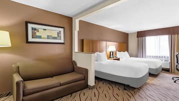 A hotel room with a brown sofa, two beds, a framed picture on the wall, and a patterned carpet.