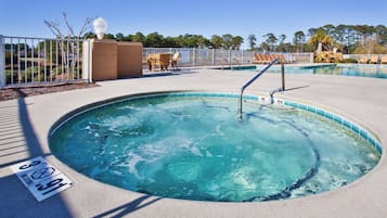 Een jacuzzi met een zwembad, omringd door een hek, en een bord met de tekst 'geen duiken toegestaan'.