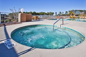 A hot tub with a pool, surrounded by a fence, and a sign indicating no diving.