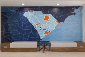A reception area with a large wall map, a wooden bench, and a round table. - Holiday Inn Express Myrtle Beach-Broadway at the Beach by IHG (Myrtle Beach)