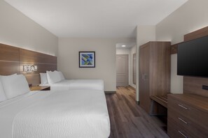 A hotel room with two beds, a TV, wooden wardrobe, and a painting on the wall.