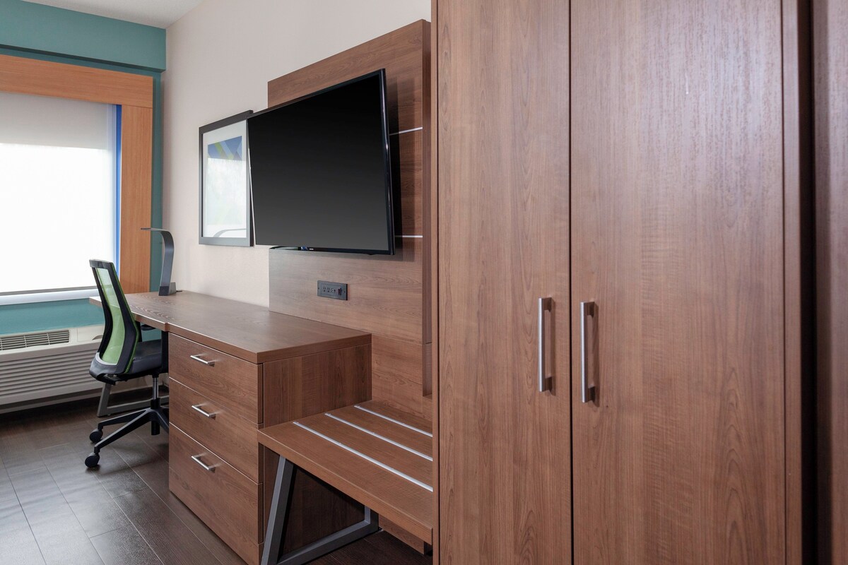 Un espace de bureau moderne avec un bureau en bois, un téléviseur à écran plat fixé au mur et une chaise.