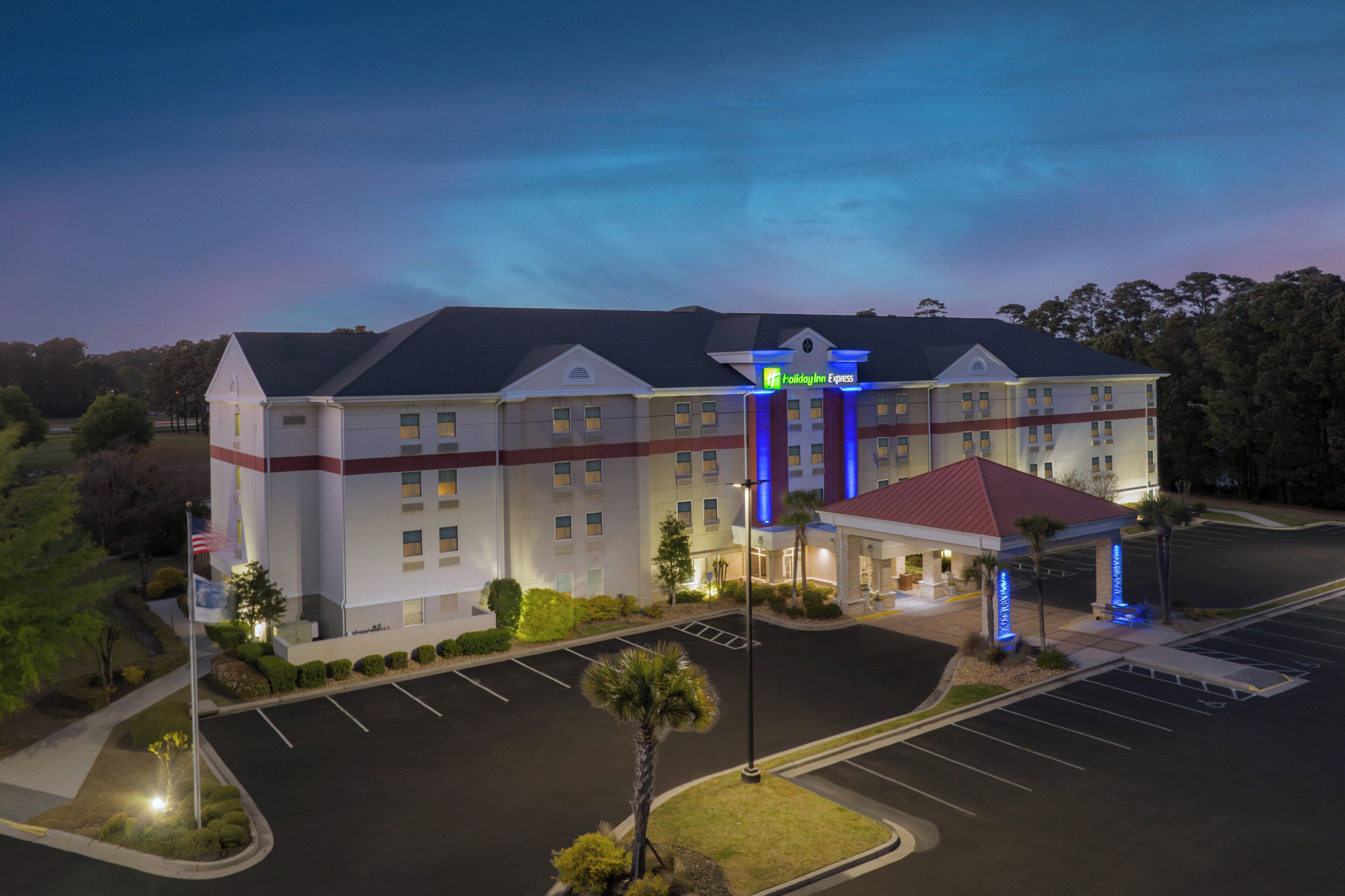 A large hotel with a prominent entrance, multiple parking lots, and a well-maintained lawn area.