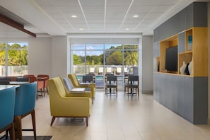 A spacious indoor area with seating, a pool view, and a television on a wall. - Holiday Inn Express Myrtle Beach-Broadway at the Beach by IHG (Myrtle Beach)
