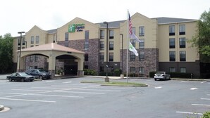 A Holiday Inn Express & Suites hotel with a stone facade, multiple parking spaces, and an American flag. - Holiday Inn Express Hotel & Suites Blythewood by IHG (Blythewood)