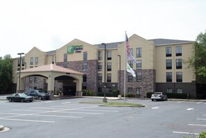 A Holiday Inn Express & Suites hotel with a stone facade, multiple parking spaces, and an American flag. - Holiday Inn Express Hotel & Suites Blythewood by IHG (Blythewood)