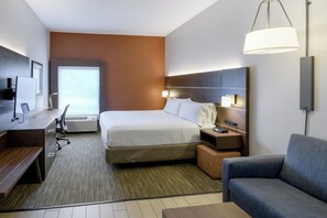 Une chambre d’hôtel équipée d’un lit, d’un bureau, d’une chaise, d’un canapé, d’une télévision et d’une lampe.
