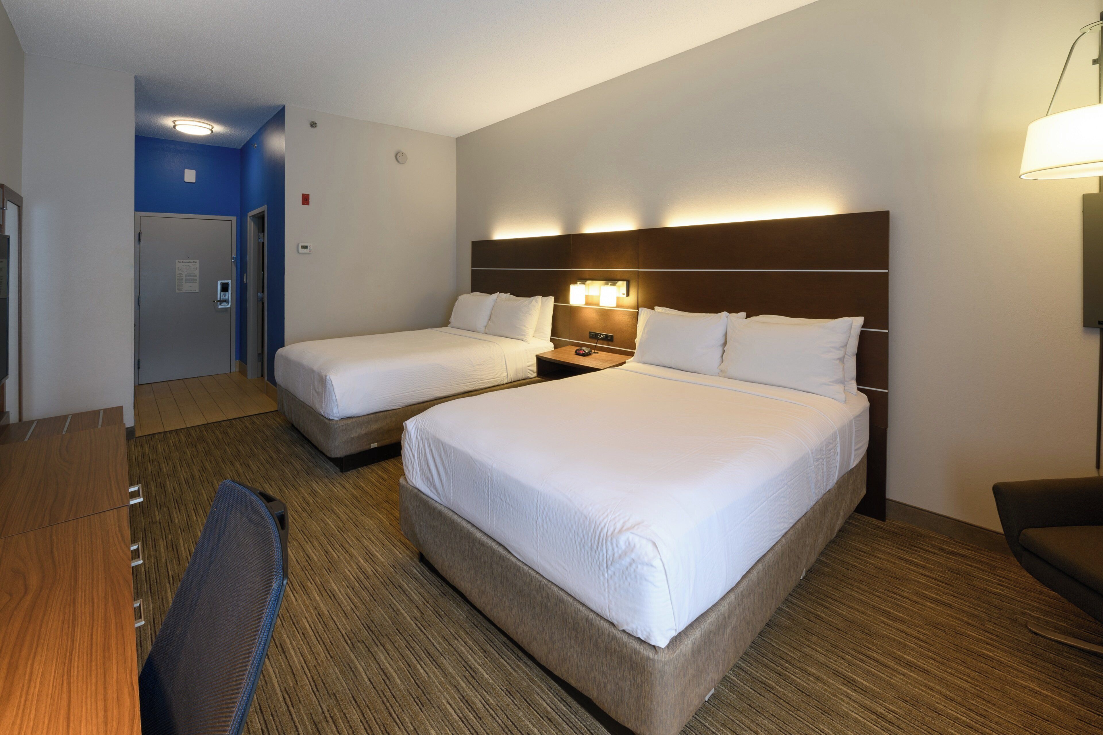 Een hotelkamer met twee bedden, een bureau en een stoel.