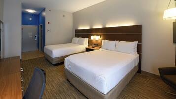 A hotel room with two beds, a desk, and a chair.