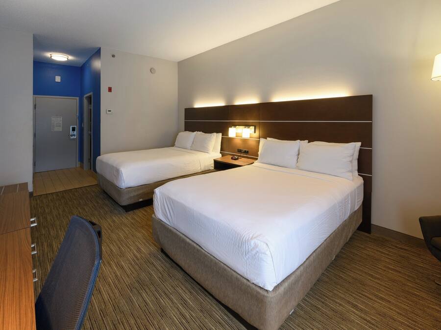A hotel room with two beds, a desk, and a chair.