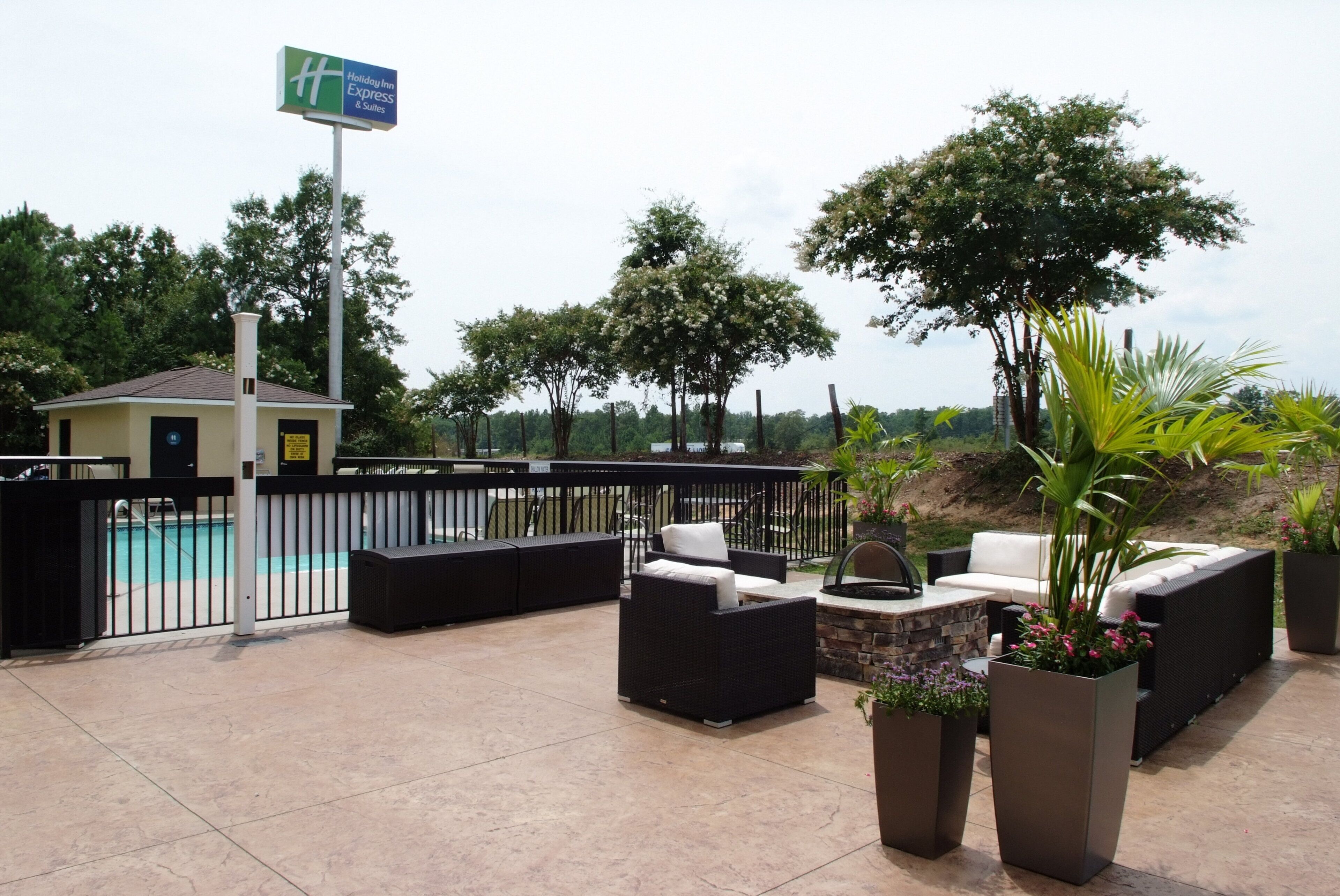 Un área de patio exterior con piscina, sillones de descanso y un cartel de Holiday Inn Express & Suites.
