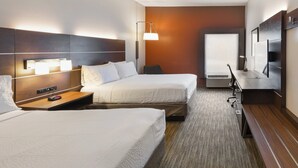 Una habitación de hotel con dos camas, un escritorio, una silla, un televisor y una ventana.