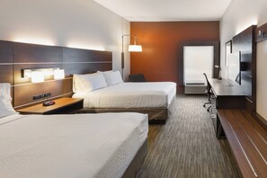 Une chambre d’hôtel avec deux lits, un bureau, une chaise, une télévision et une fenêtre.