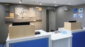A hotel reception desk with a sign for Holiday Inn Express Suites, a security camera, and a no-smoking sign. - Holiday Inn Express Hotel & Suites Blythewood by IHG (Blythewood)