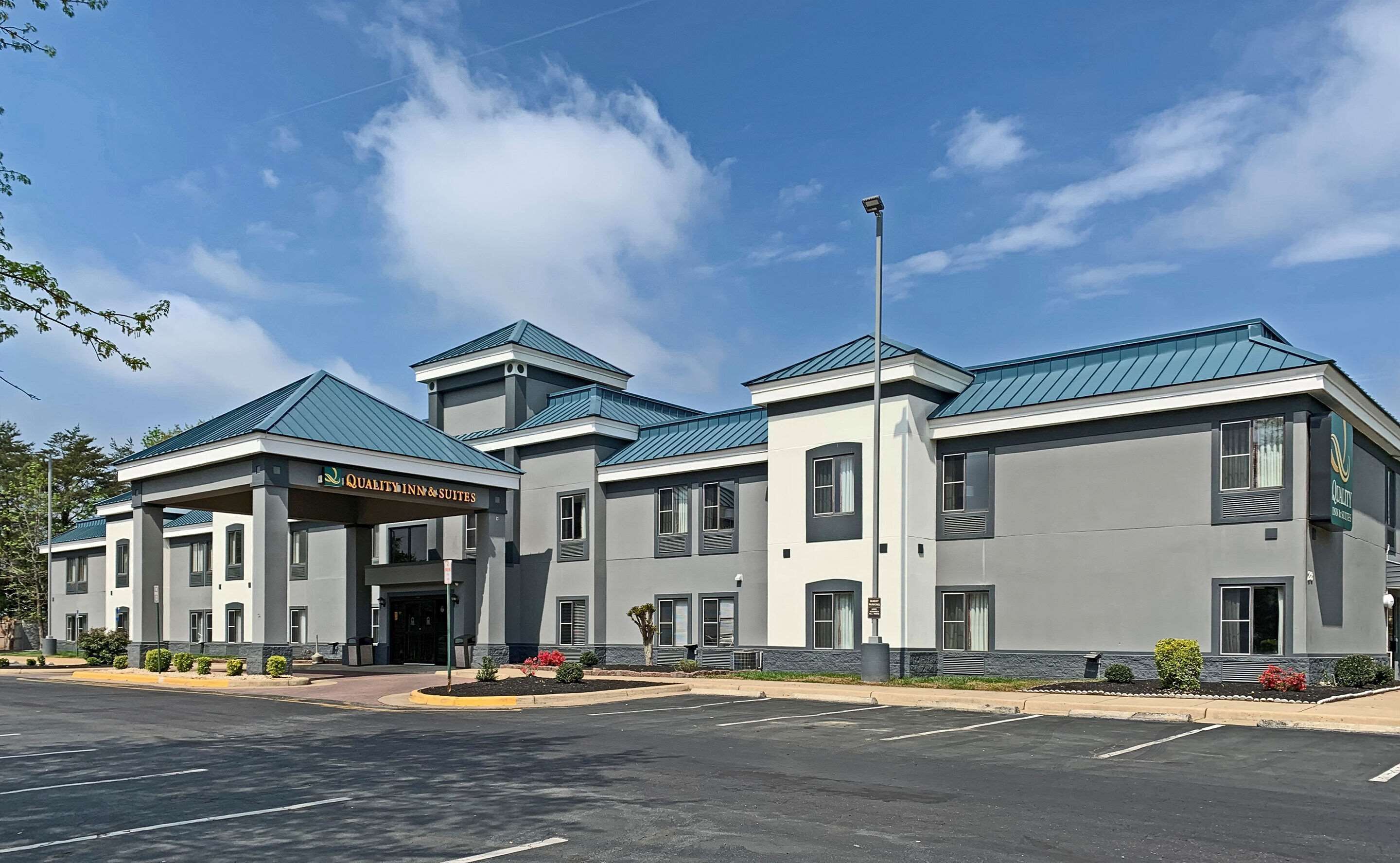A multi-story hotel with a modern design, featuring a prominent entrance with a sign reading "Quality Inn & Suites."