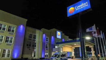 A Comfort Inn & Suites hotel with a sign, a van, and a flag.