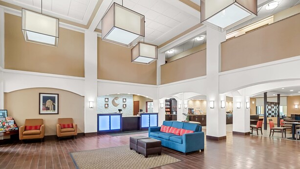 A spacious lobby with a reception desk, seating area, and a kitchen in the background. - Comfort Inn & Suites (Allen Park)