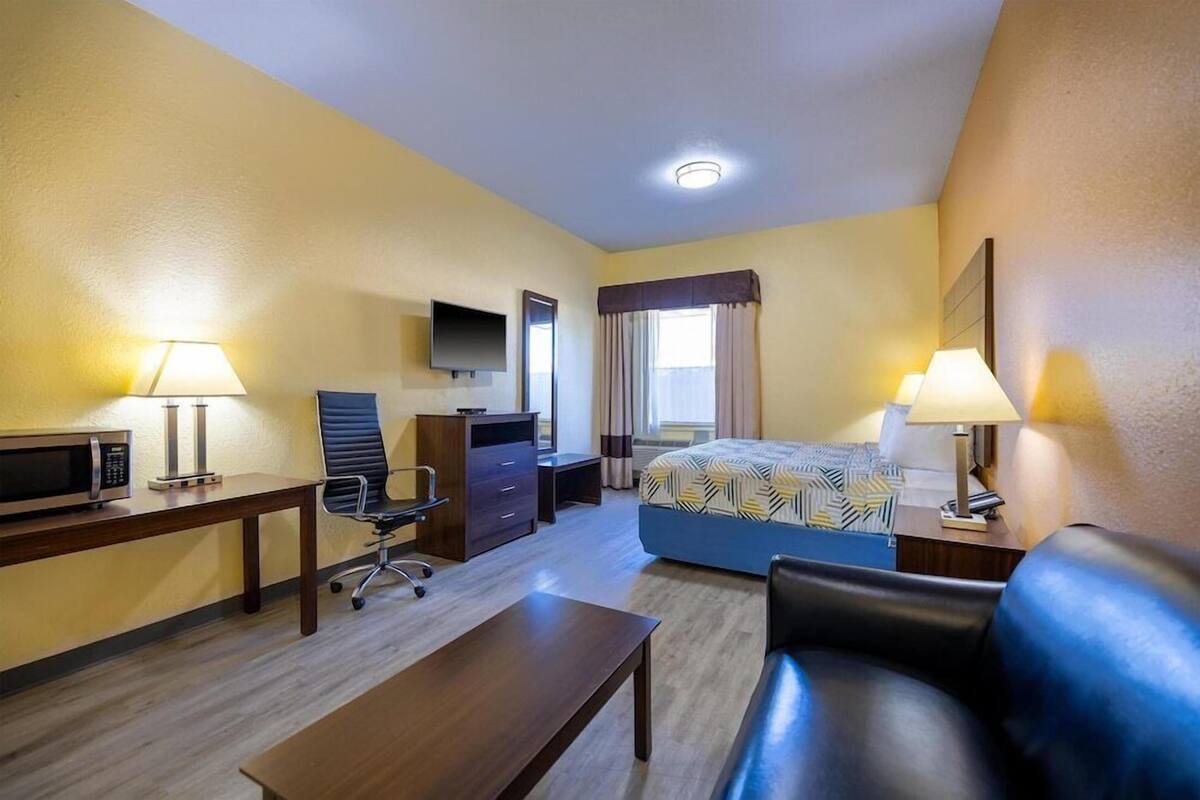 Une chambre d’hôtel équipée d’un lit, d’un bureau, d’une chaise, d ’un canapé, d’une télévision et d’une lampe.