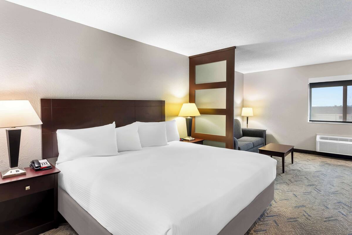 A hotel room with a large bed, two bedside tables, a chair, a desk, and a window.
