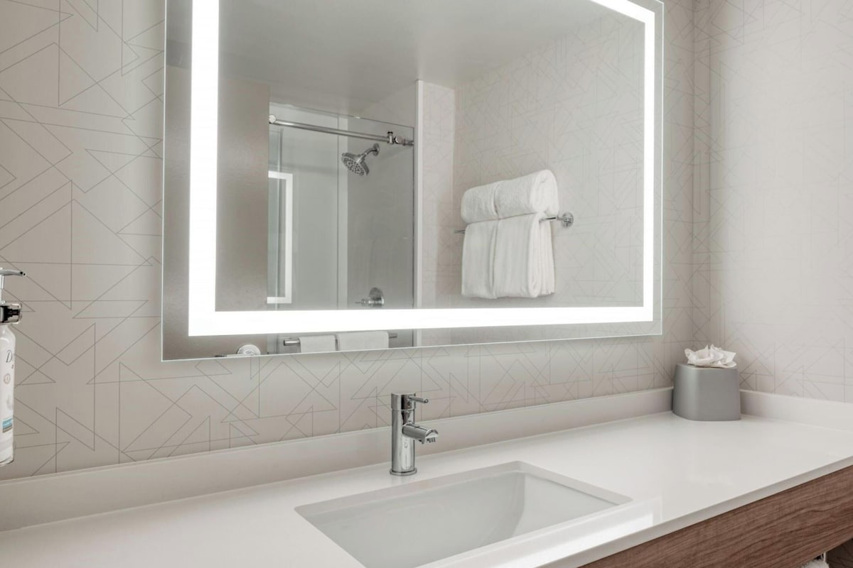Une salle de bain moderne avec un grand miroir, un lavabo et un porte-serviettes.