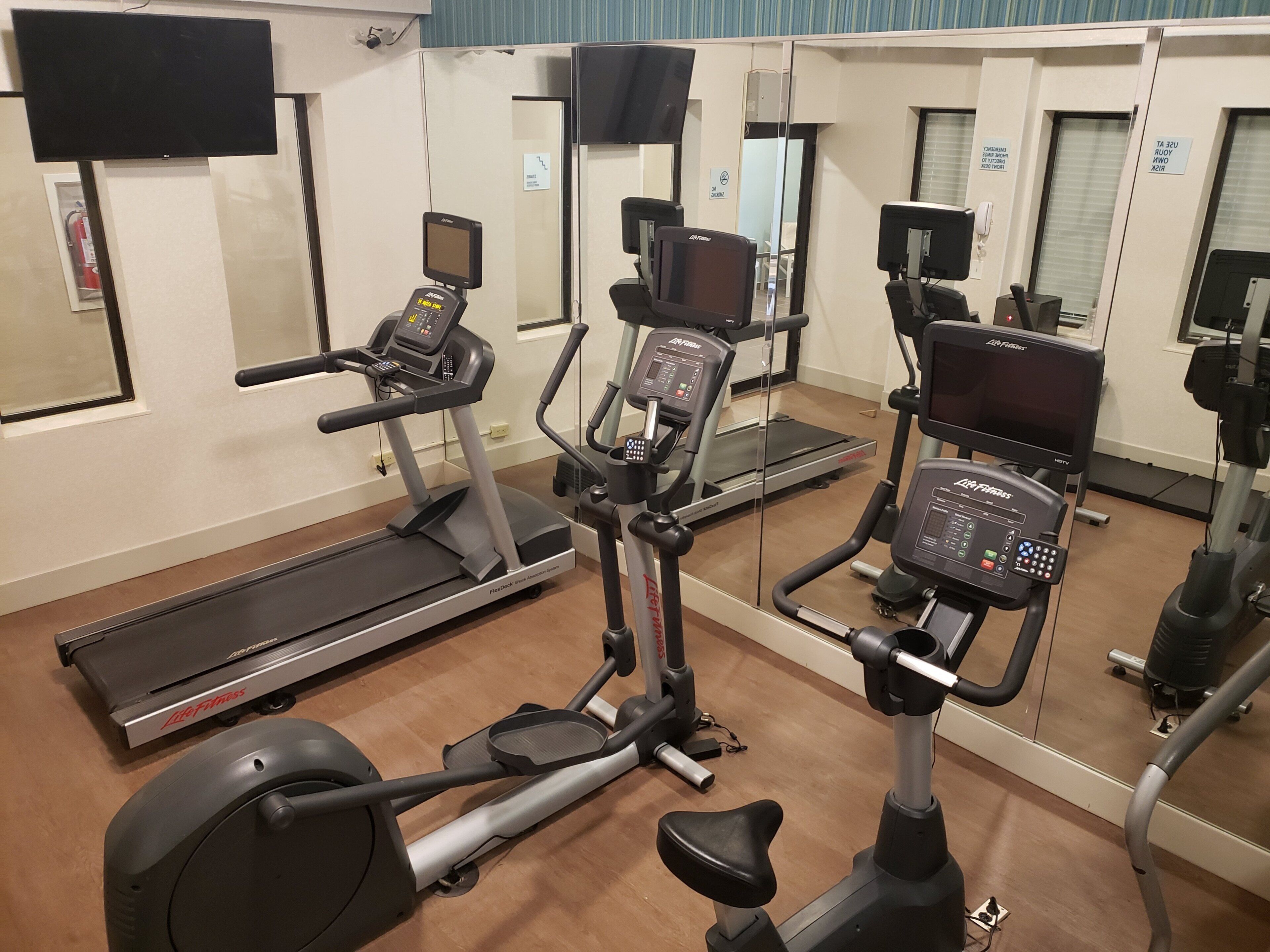 A gym with various exercise equipment including treadmills, an elliptical, and a stationary bike.