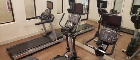 A gym with various exercise equipment including treadmills, an elliptical, and a stationary bike.