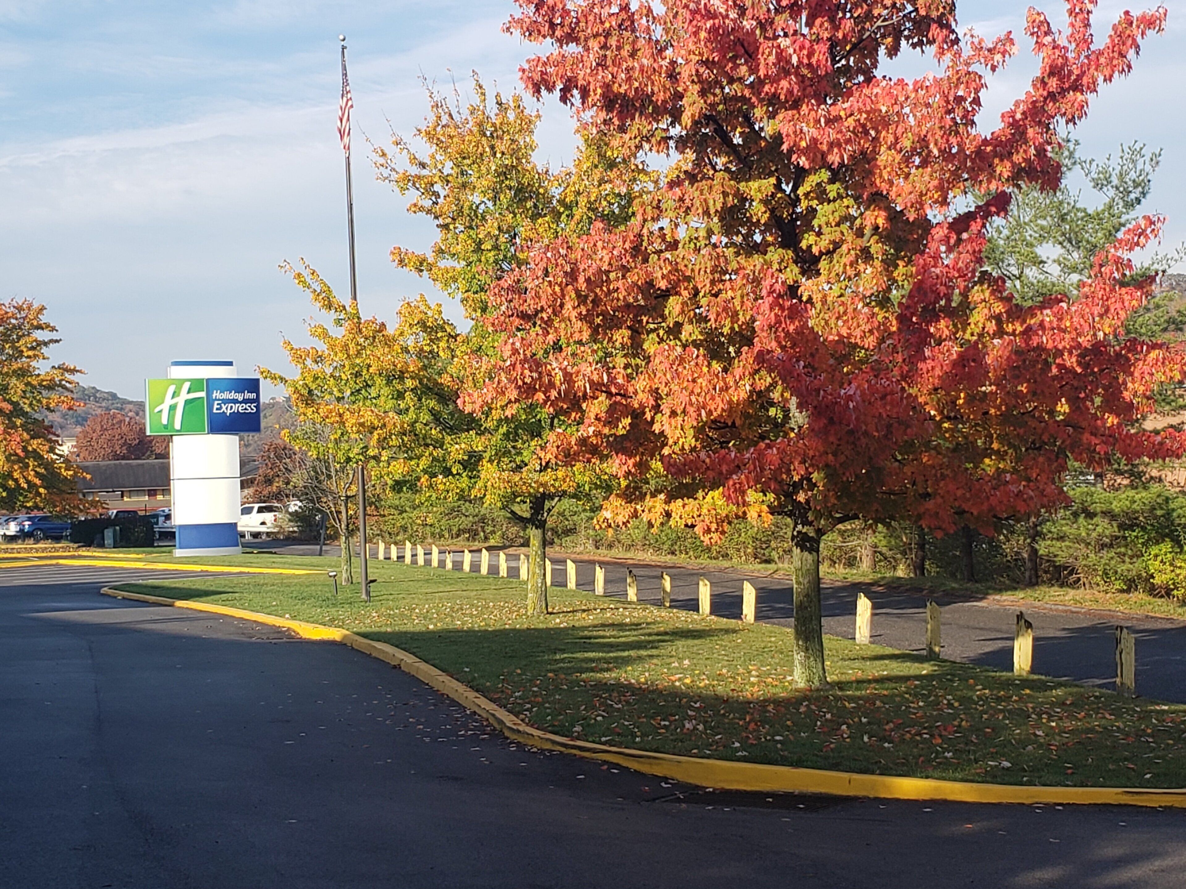 A Holiday Inn Express sign, a parking lot, and autumn-colored trees.