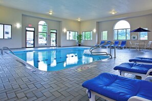 An indoor swimming pool with clear lanes, a lifeguard chair, and lounge chairs.