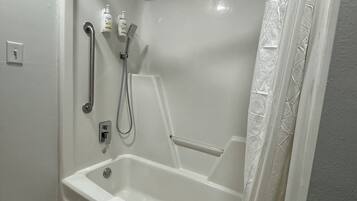 A modern bathroom with a walk-in shower, grab bars, and a handheld showerhead.