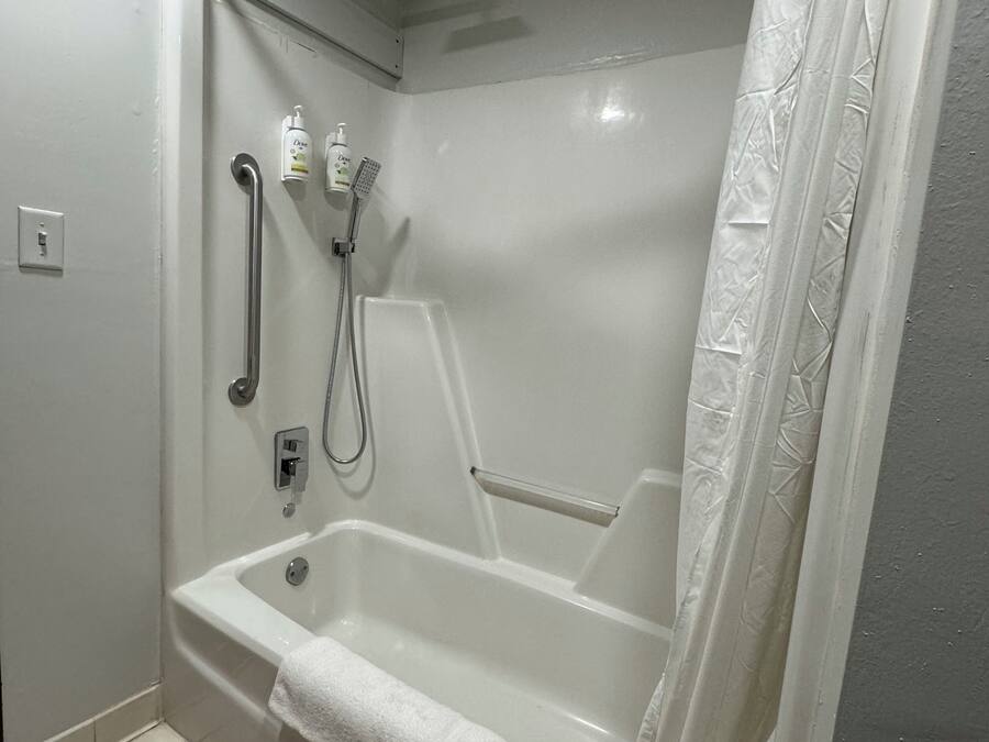 A modern bathroom with a walk-in shower, grab bars, and a handheld showerhead.