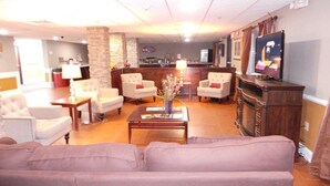 A spacious living room with a sofa, armchairs, a coffee table, and a television. - Lux Hotel (Cordele)