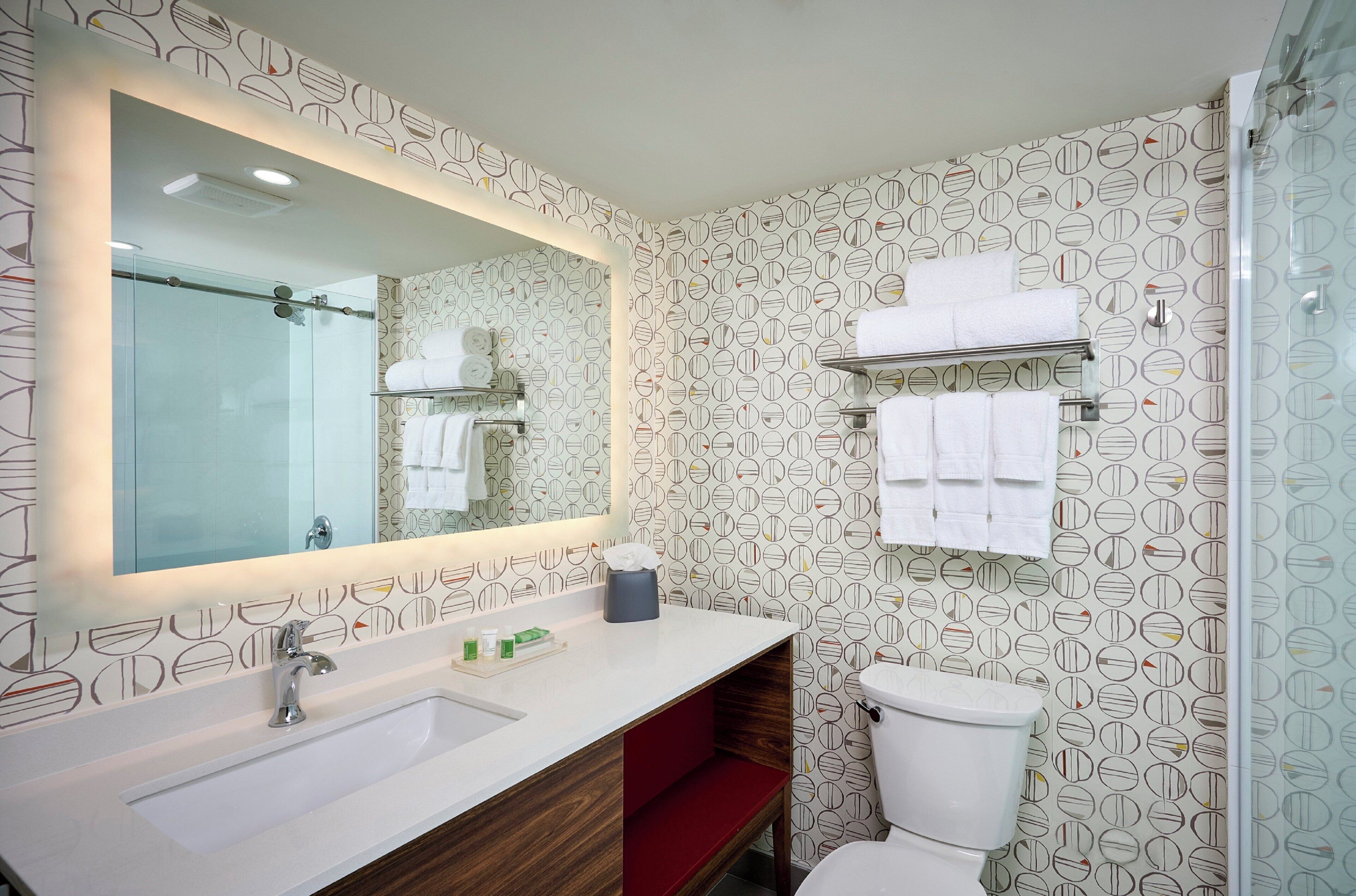 Een badkamer met een grote spiegel, een wastafel, een toilet en een douche.