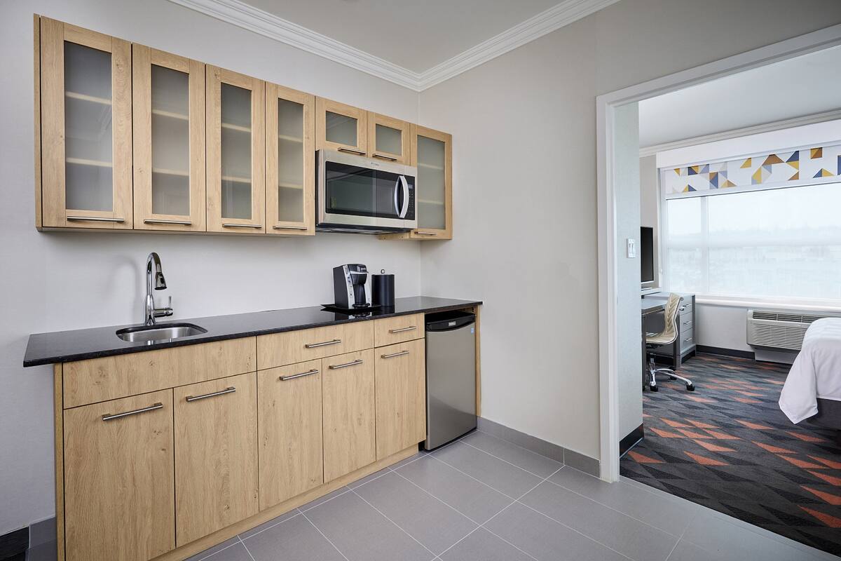 A modern kitchen with wooden cabinets, a stainless steel sink, and a microwave.
